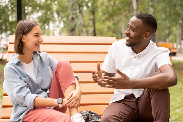 male and female friends chatting on park bench