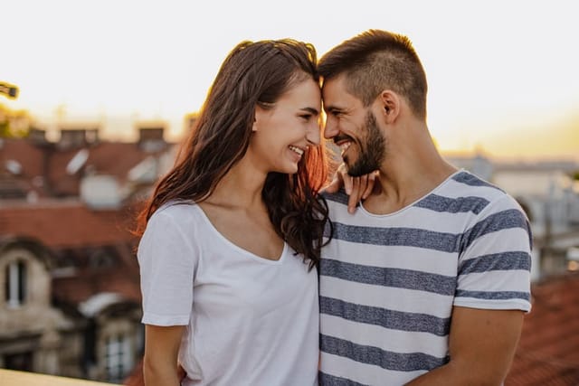 Photo of a young couple on the rooftop, enjoying the moment, they are embracing