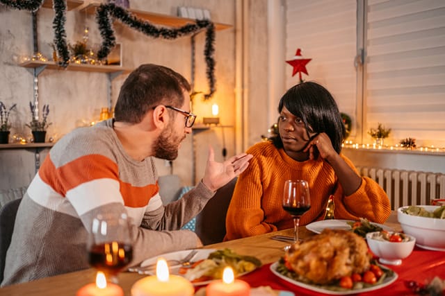 man lecturing woman at dinner table