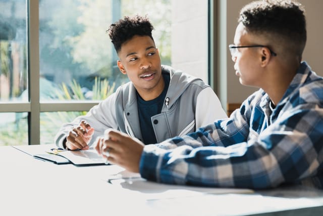 two guys having a convo at a desk