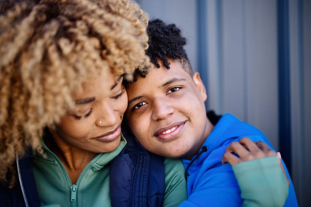 ortrait of a smiling mature woman and her fifteen years old boy, embracing and kissing