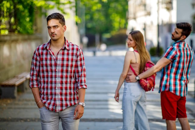 Young woman makes a jealous situation while walking around the city with her boyfriend