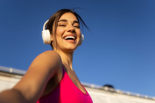 smiling woman with headphones in sunshine