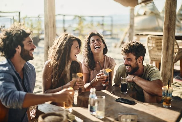 Group of cheerful friends communicating while spending a summer day in a beach café.