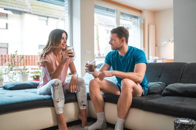 Happy mid adult mixed race couple dirnking a healthy smoothie at home. They are enjoying an active lifestyle together.