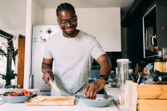 millennial man cooking food in kitchen
