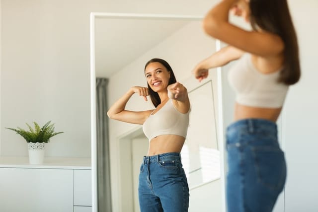 Cheerful Lady Pointing At Her Reflection In Mirror At Home