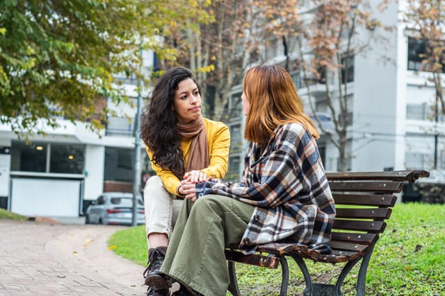 female friends chatting on a park bench