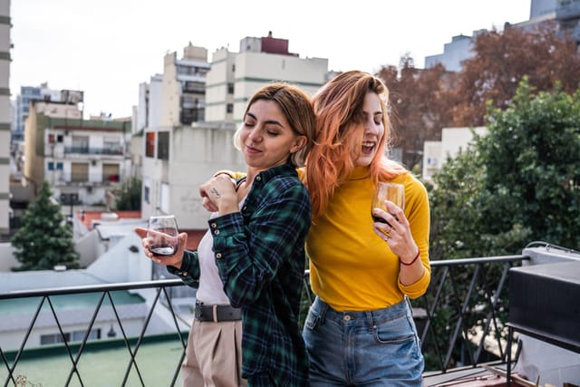 two friends drinking wine on rooftop