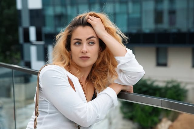 Woman with blond hair looks away with a thoughtful look