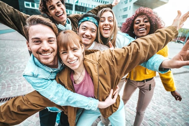 Multi ethnic young people smiling together at camera outside - Happy multiracial friends having fun walking on city street - Life style concept with guys and girls hanging out on summer vacation