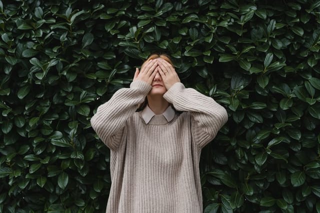 Portrait of relaxed woman with eyes closed on background of green leaves wall. Concept of outside of office, Work-Life-Balance, Taking Break. Zen and balance people. Stability through mental health.