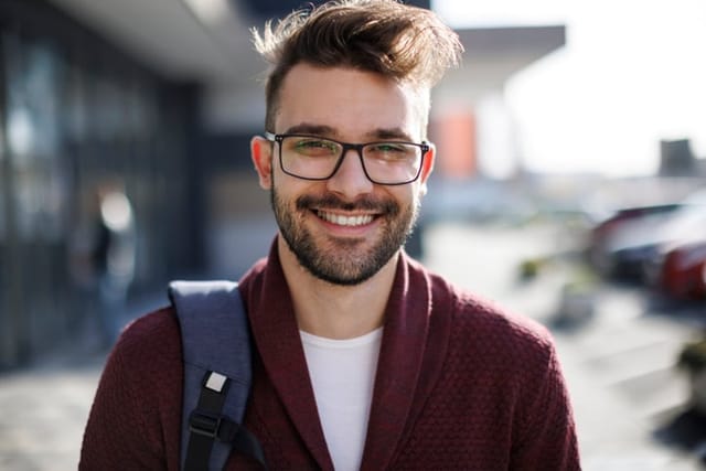 smiling man with glasses and backpack