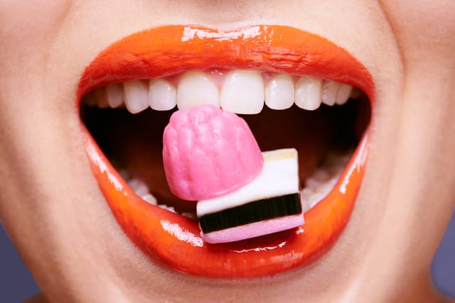Cropped shot of a beautiful young woman eating liquorice 