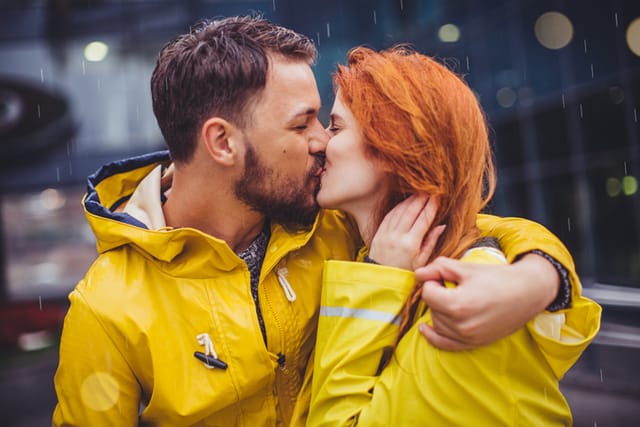 Couple having fun at rain. Wearing raincoats and enjoying in their love. It's raining and it's night outside at city.