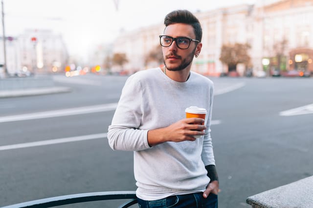 hipster with coffee crossing street