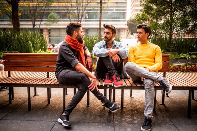 three male friends chatting on bench