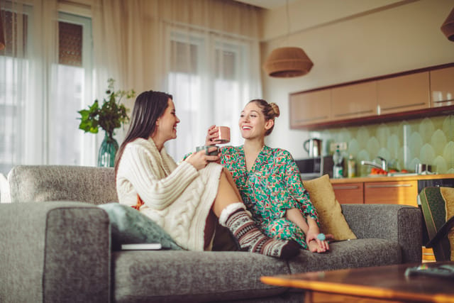 two women sitting at home in PJs chatting