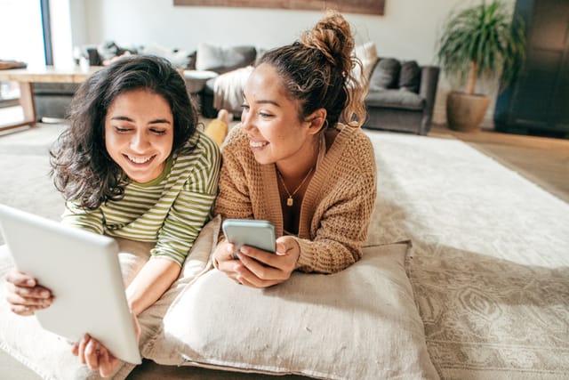 two women laying in bed talking