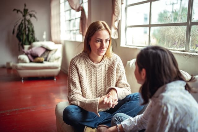 two women chatting on a couch