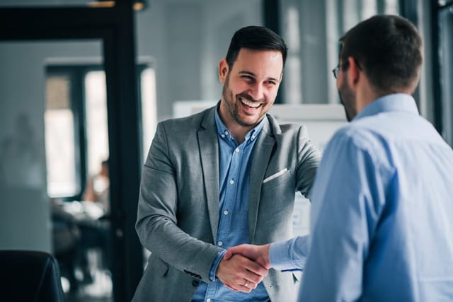 smiling man shaking hands with fellow businessman