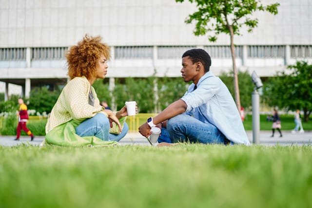 male and female friend sitting in grass talking