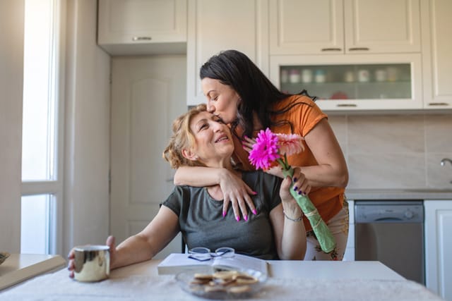 woman kissing mother's head reading book