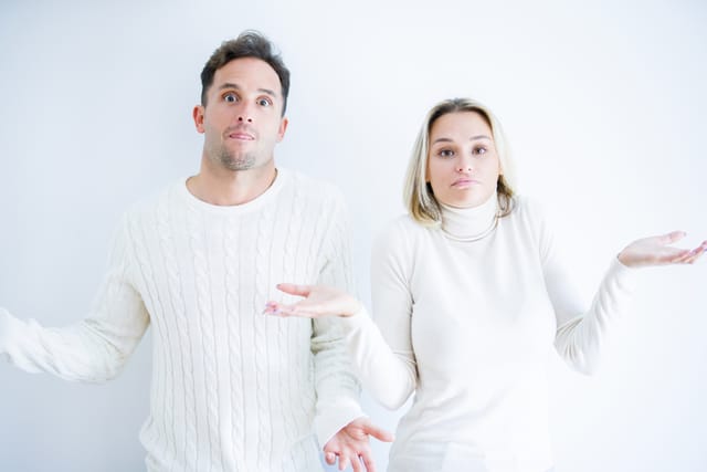 Young beautiful couple wearing casual t-shirt standing over isolated white background clueless and confused expression with arms and hands raised. Doubt concept.