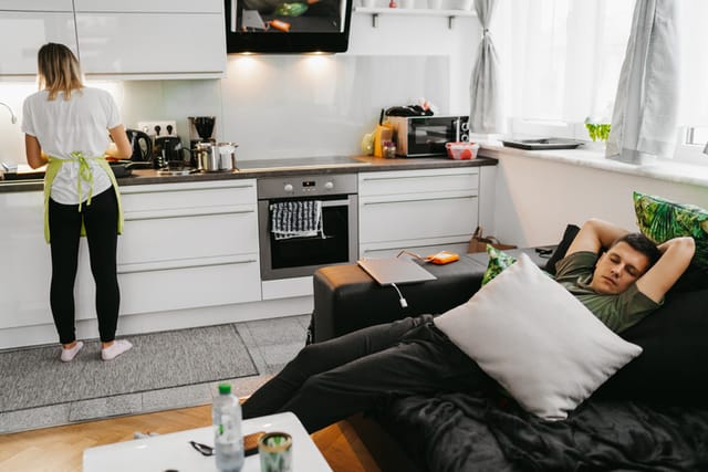 woman cooking while man naps on couch