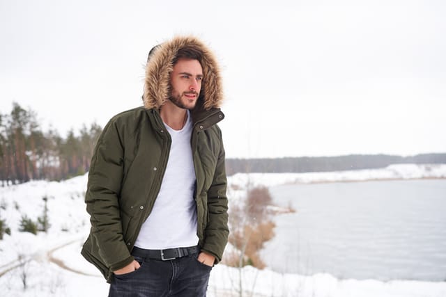 Man wearing heavy jacket, walking through snow.