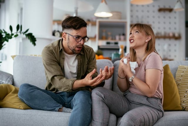 Boyfriend and girlfriend are arguing on the couch. Angry woman is yelling at her boyfriend.