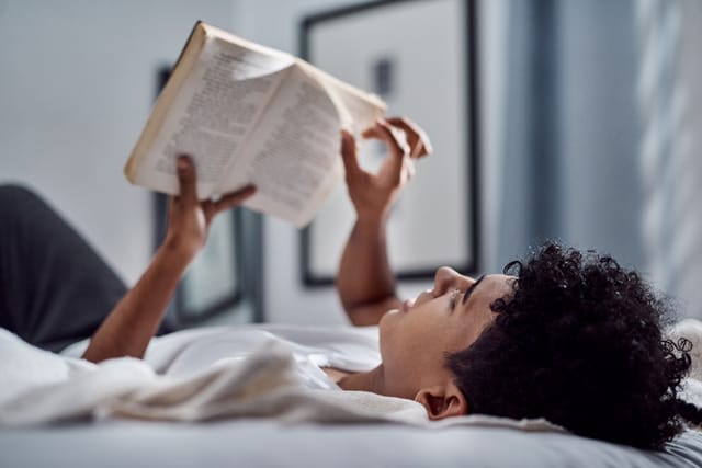 man laying down in bed reading
