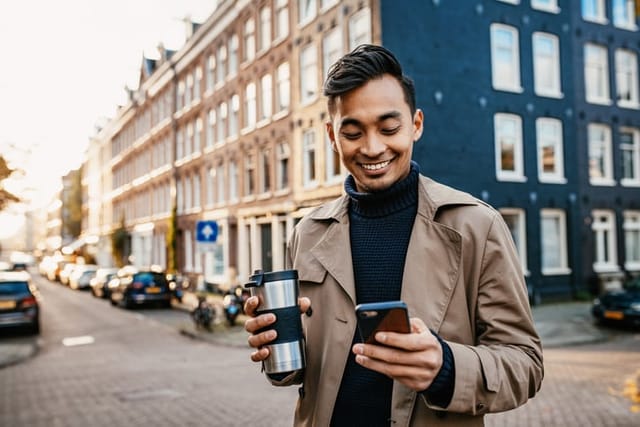 smiling man checking his phone with coffee
