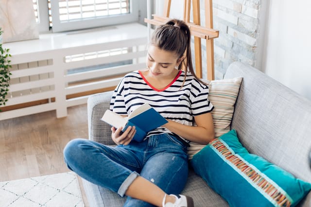 Portrait of a beautiful girl enjoying reading a book at home.