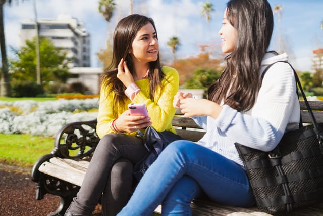 two women having a conversation on park bench