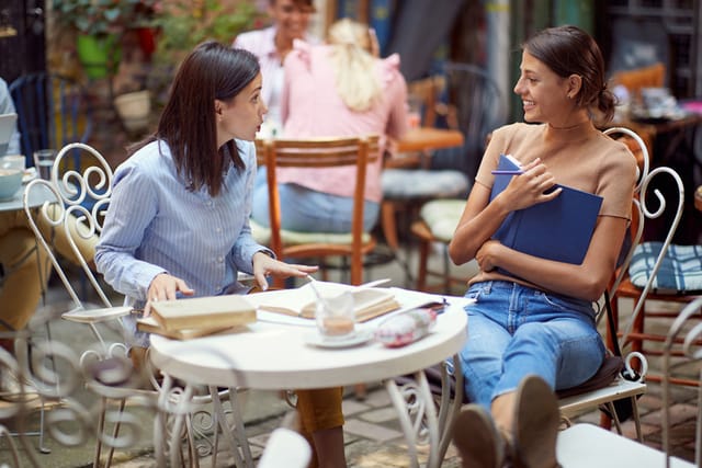 two female friends chatting at cafe outside