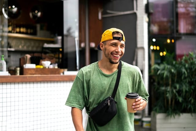 smiling guy walking with coffee cup outside