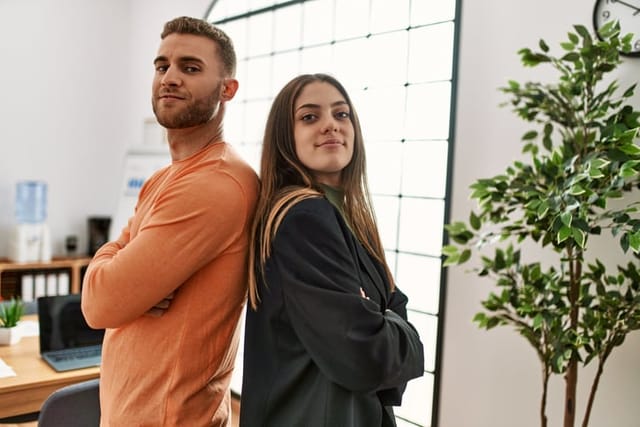 Two caucasian business executives with arms crossed gesture standing at the office.