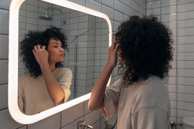 woman examining her skin in the mirror