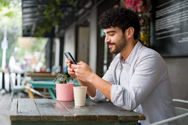 man texting at outdoor cafe