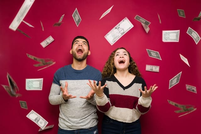 aining money. Excited young man and woman with a lot of cash feeling very rich after earning their paycheck