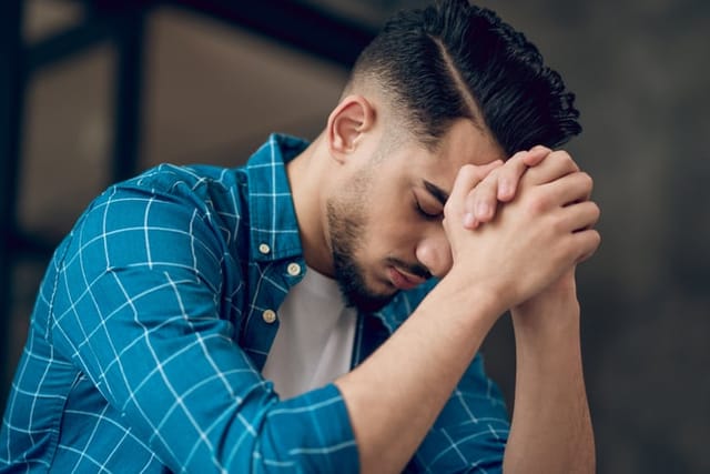 Stressed. Young dark-haired man sitting with an unhappy look