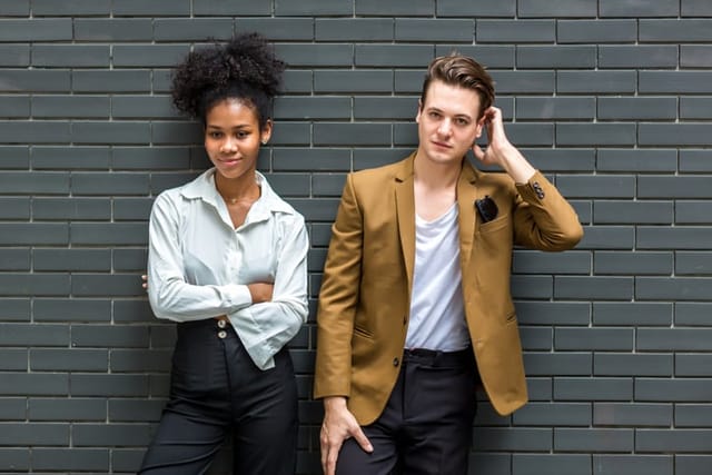 A Diverse couple - Multi-ethnic couple in love. African American woman and a Caucasian man standing background wall. Portrait of a diverse young couple standing on background wall brick