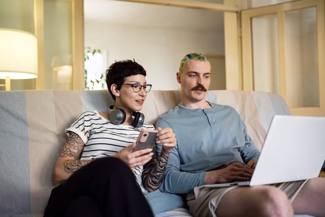 woman looking at man's computer on couch