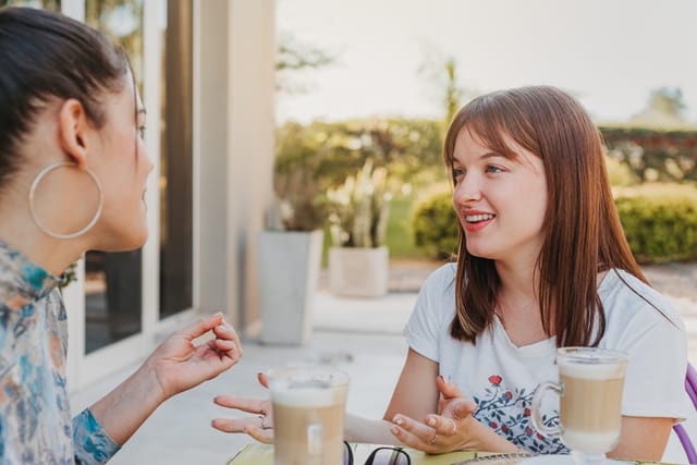 two women chatting outside with drinks