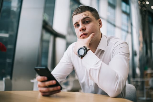 young businessman using phone looking serious