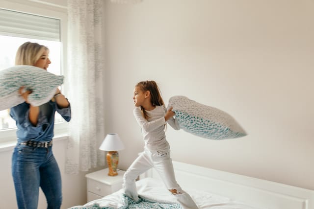 mom and daughter having pillow fight