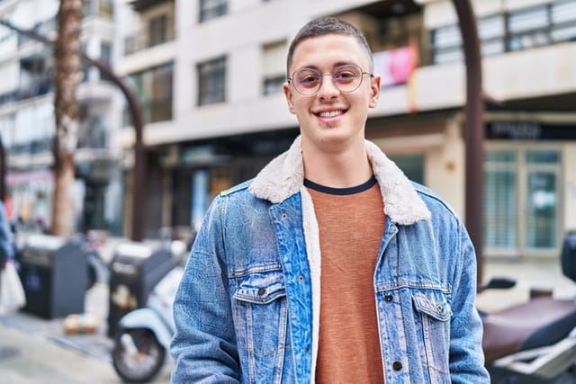 young smiling millennial guy in street