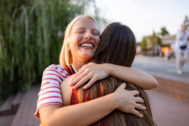 happy woman hugging friend on sunny day
