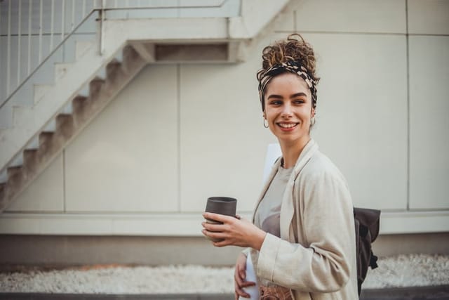 smiling businesswoman walking with coffee